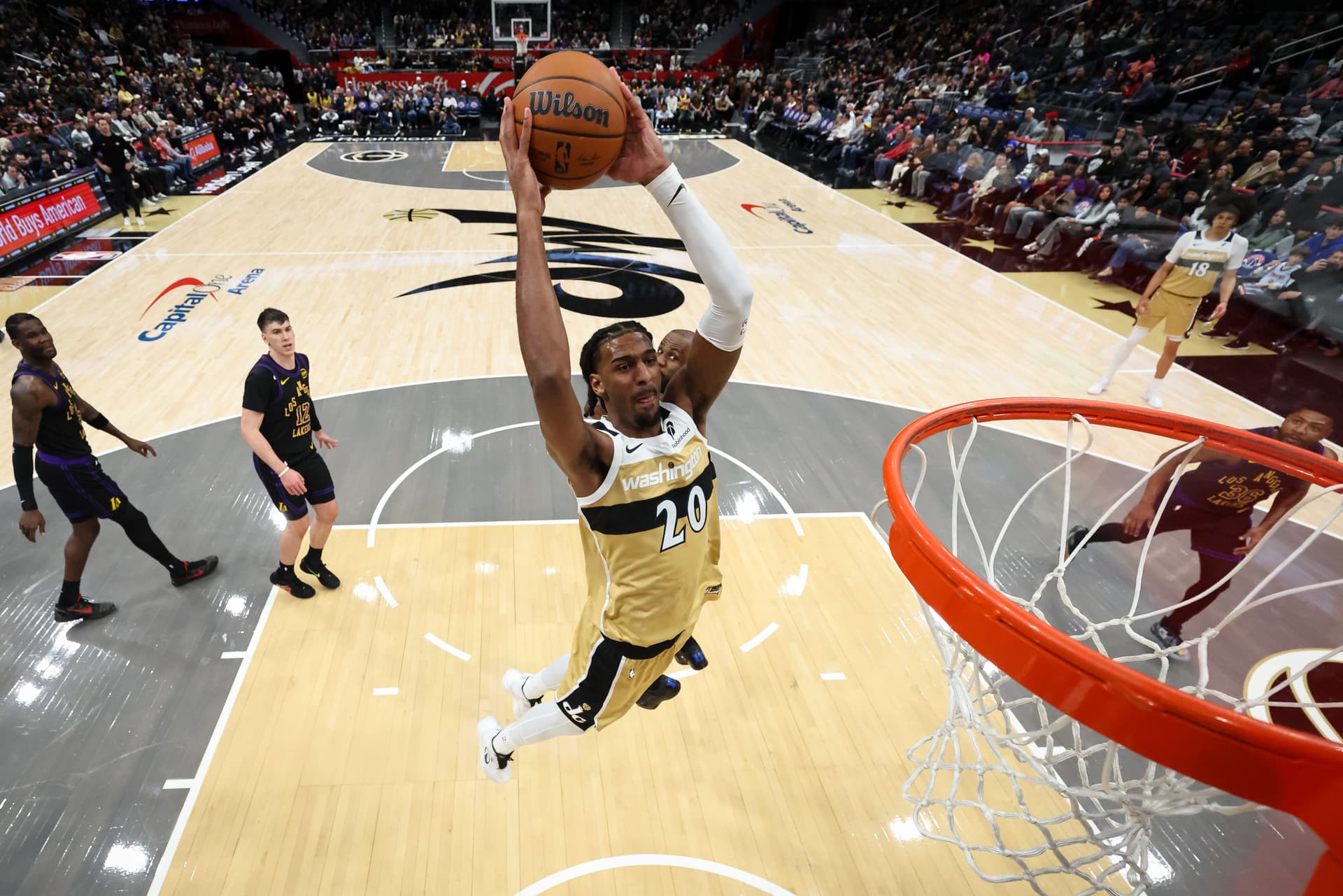 Alex Sarr #20 of the Washington Wizards dunks the ball in front of LeBron James #23