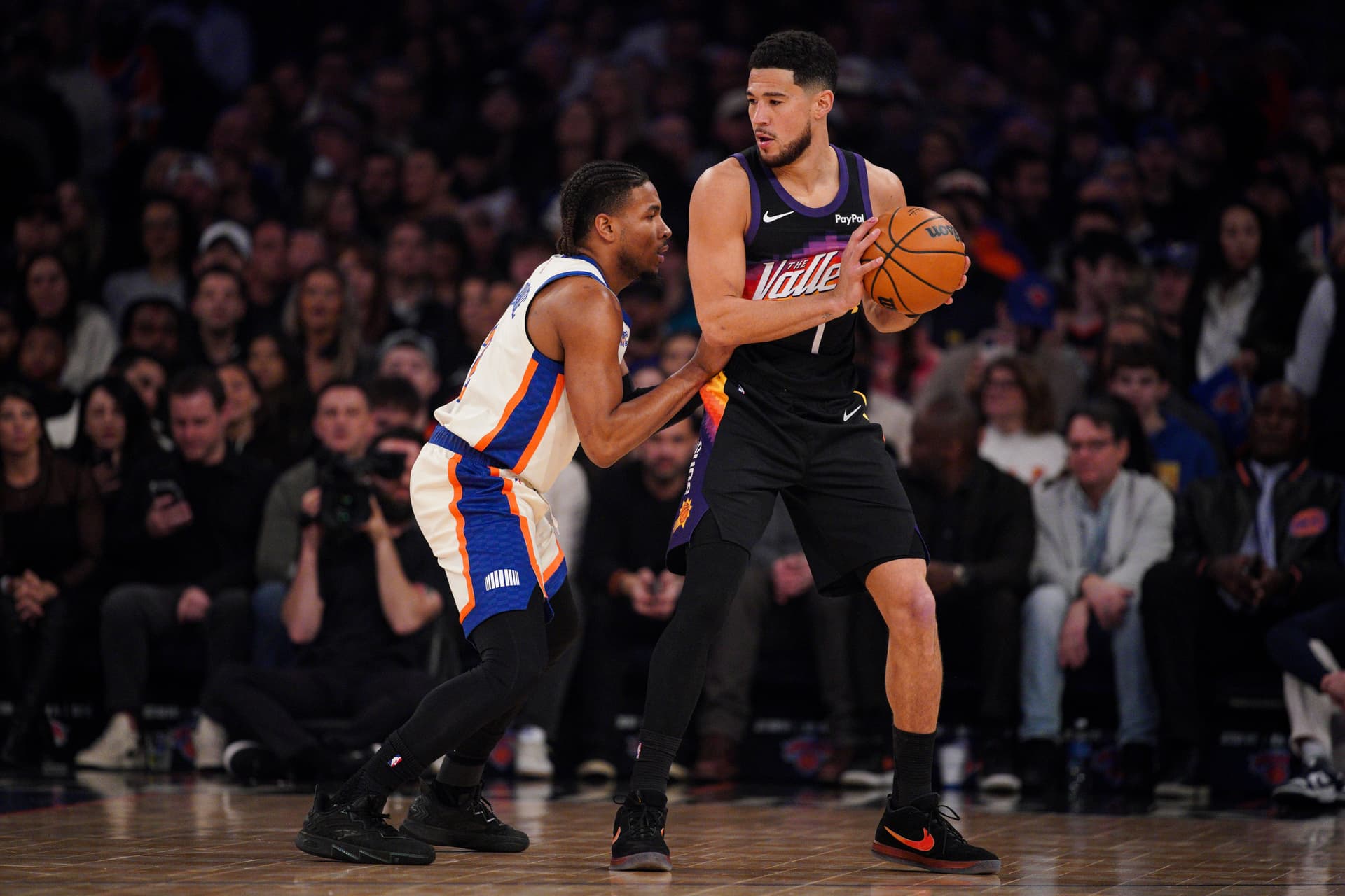 Devin Booker #1 of the Phoenix Suns handles the ball as Miles McBride #2