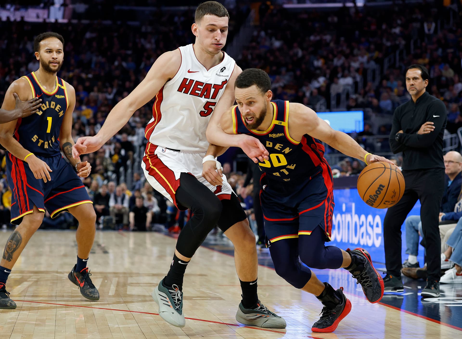 Stephen Curry dribbling the ball is guarded by Nikola Jovic